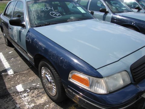 2001 Ford Crown Victoria - A 2001 Ford Crown Victoria police car is parked in a lot with other vehicles.