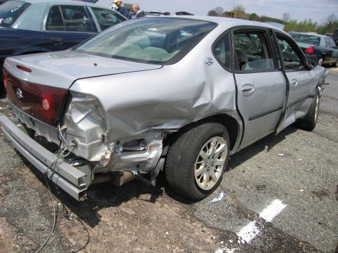 2001 Ford Crown Victoria - This silver sedan has suffered severe damage to its rear and side, with the bumper missing and body panels heavily dented.