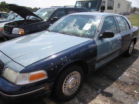 2001 Ford Crown Victoria - A 2001 Ford Crown Victoria is parked outdoors with other vehicles, showing a two-tone paint scheme.