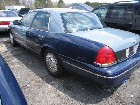 2001 Ford Crown Victoria - This sedan has a dark blue lower body and a light blue upper body and roof, with visible damage to the rear window.