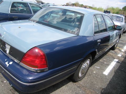 2001 Ford Crown Victoria - A two-tone blue Ford Crown Victoria is parked in a lot with other vehicles.
