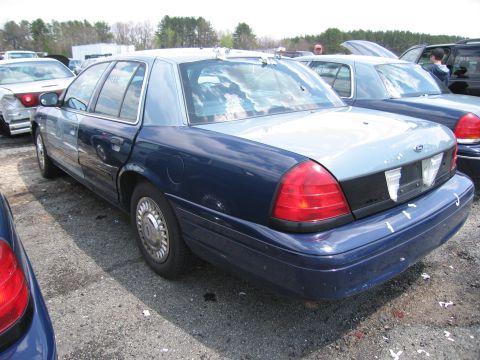 2001 Ford Crown Victoria - A two-tone Ford Crown Victoria is parked in a lot with other vehicles.