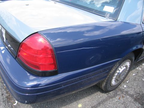 2001 Ford Crown Victoria - Rear view of a blue 2001 Ford Crown Victoria, showing the taillight and quarter panel with visible scratches.