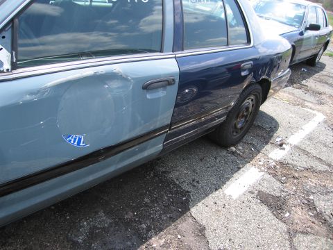 2001 Ford Crown Victoria - The driver's side of this sedan has been painted two different shades of blue and shows significant damage.