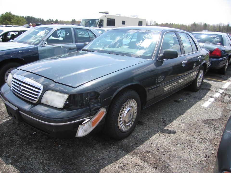 Dark green 2001 Ford Crown Victoria sedan, 3q front view, with damage to front passenger side