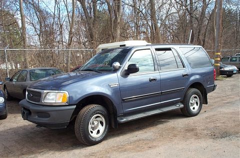 2001 Ford Crown Victoria - This blue SUV, likely a 2001 Ford Expedition, is seen parked in an outdoor lot with other vehicles.