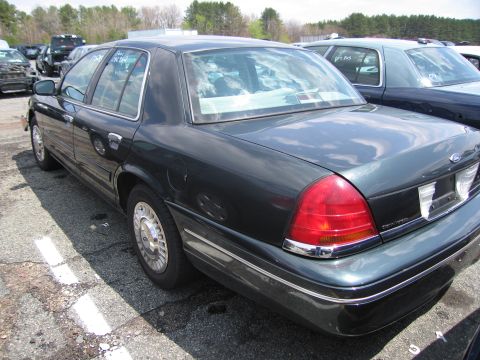 2001 Ford Crown Victoria - Rear view of a dark green 2001 Ford Crown Victoria parked in a lot with other vehicles.
