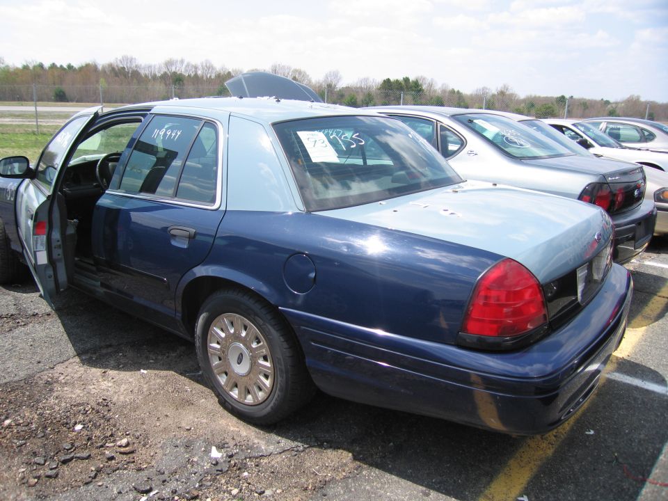 Two-tone blue Ford Crown Victoria sedan with door open in a lot