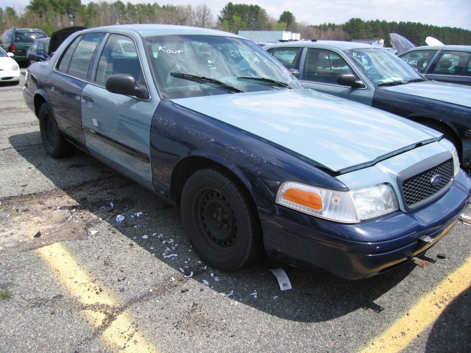 Two-tone blue Ford Crown Victoria with damage parked in a lot