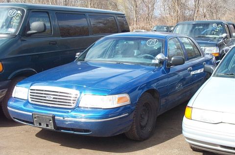 2001 Ford Crown Victoria - This blue 2001 Ford Crown Victoria sedan is seen in a lot with other vehicles.