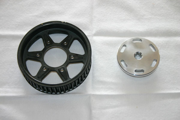 Black pulley and silver circular part on white surface