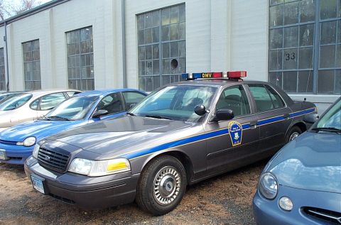 2001 Ford Crown Victoria - A police car, identified as a 2001 Ford Crown Victoria, is parked in a lot with other vehicles.
