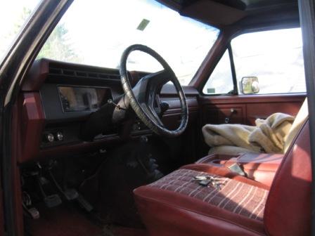 1993 Ford Bronco - Interior of an older Ford truck shot from the passenger door, showing a red vinyl bench seat, red door panels and a black dash with a colum…