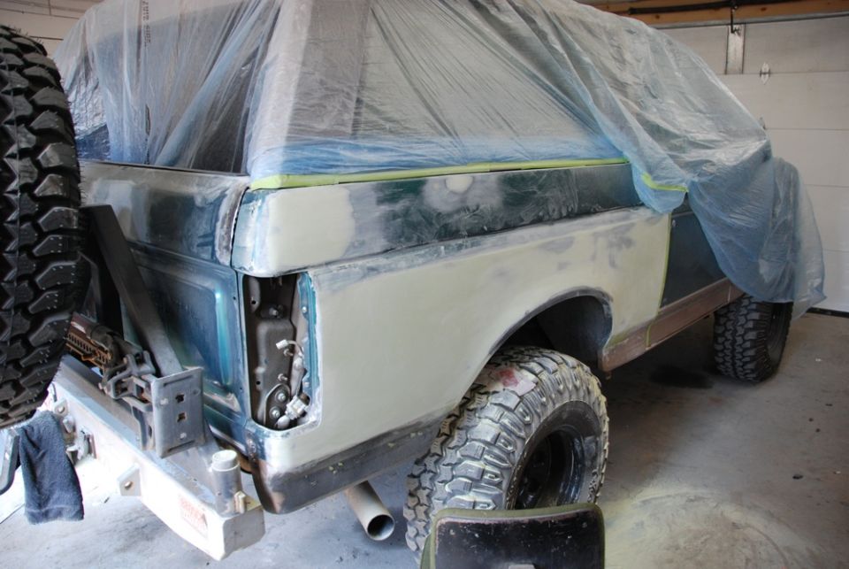 Photo of a Bronco/truck body in primer with plastic sheeting in a garage