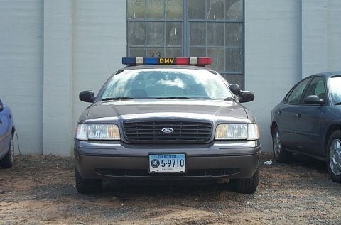 2001 Ford Crown Victoria - A 2001 Ford Crown Victoria police car is parked in front of a building with a DMV light bar on top.