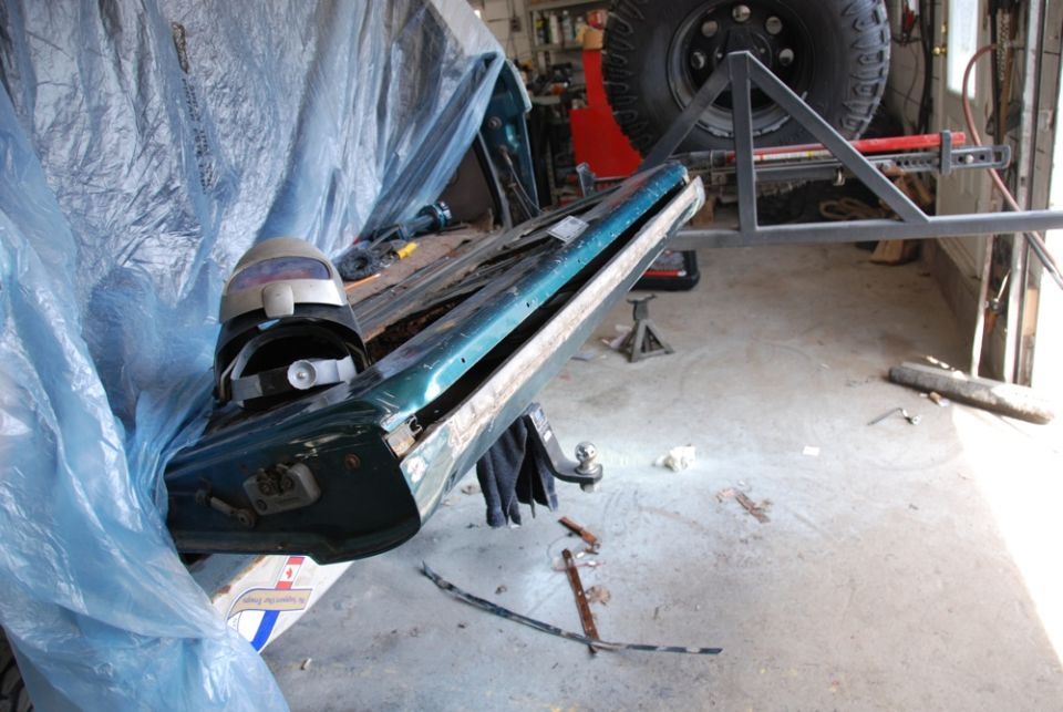 Photo of a teal truck body panel propped against plastic sheeting in a shop