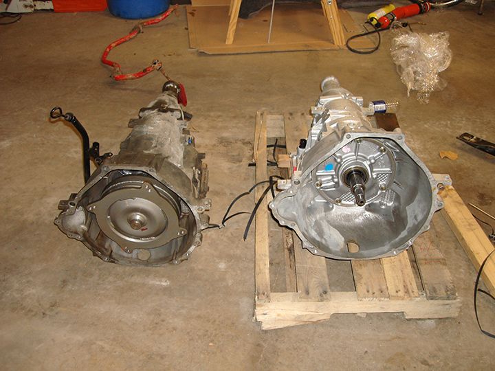 Two automatic transmissions, one used and one new, on a concrete floor.