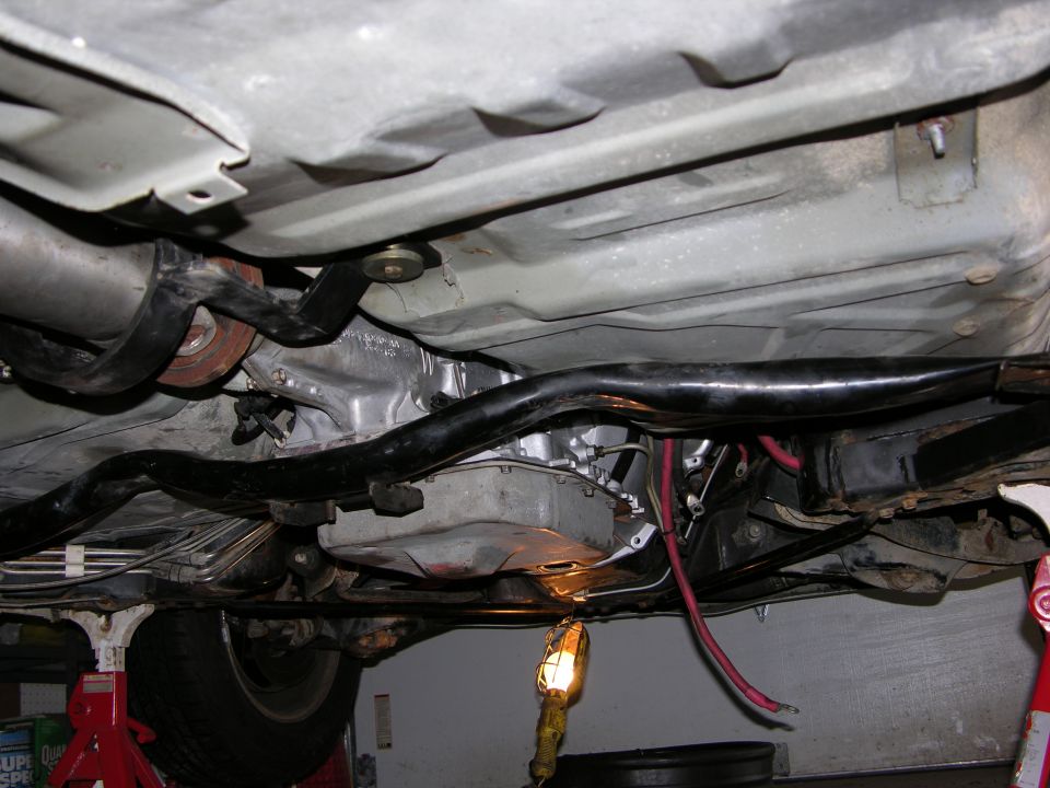 Underside of a vehicle showing transmission, exhaust, and frame components.