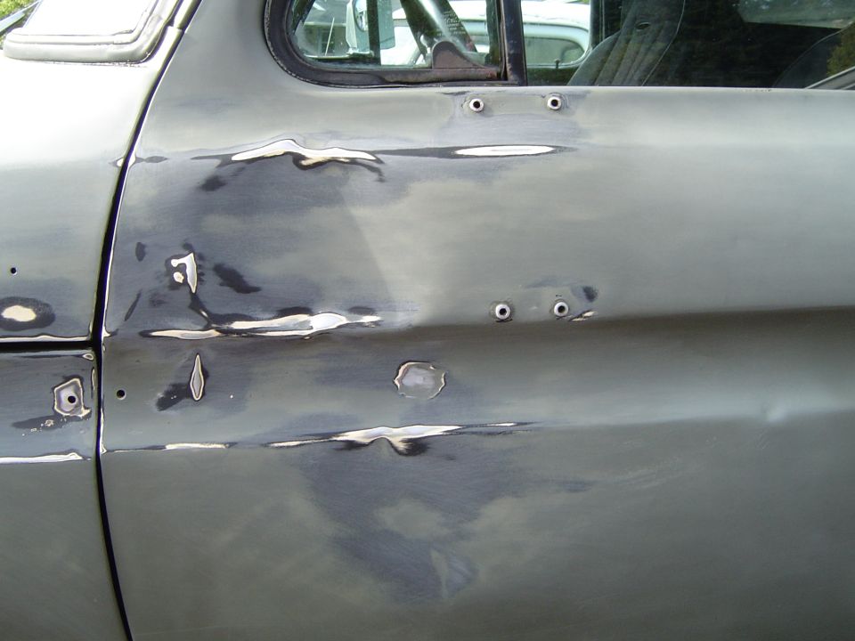 Sanded and primer-spotted door and body panel of a vehicle in bodywork