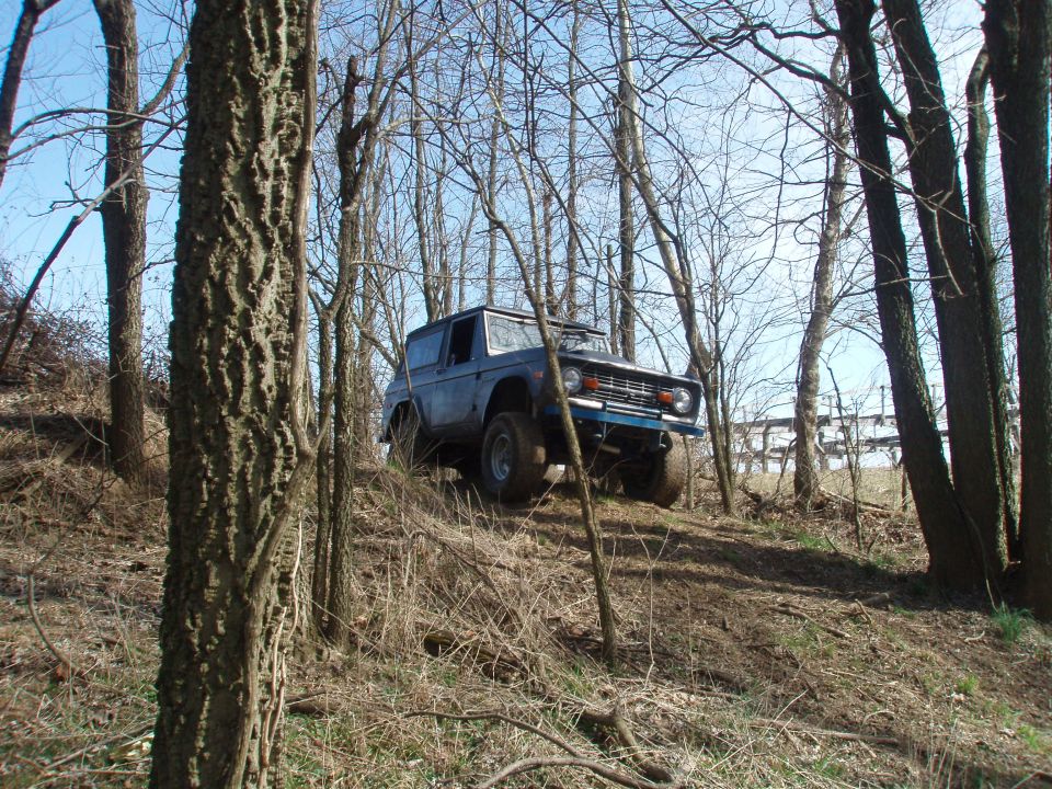 Blue 1971 Ford Bronco parked on a wooded hill.