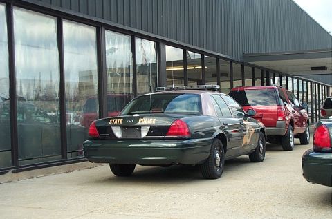 2001 Ford Crown Victoria - Rear view of a police car, likely a 2001 Ford Crown Victoria, parked outside a building.