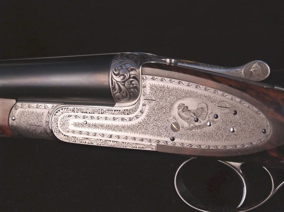 Close-up of engraved shotgun receiver with bird motif