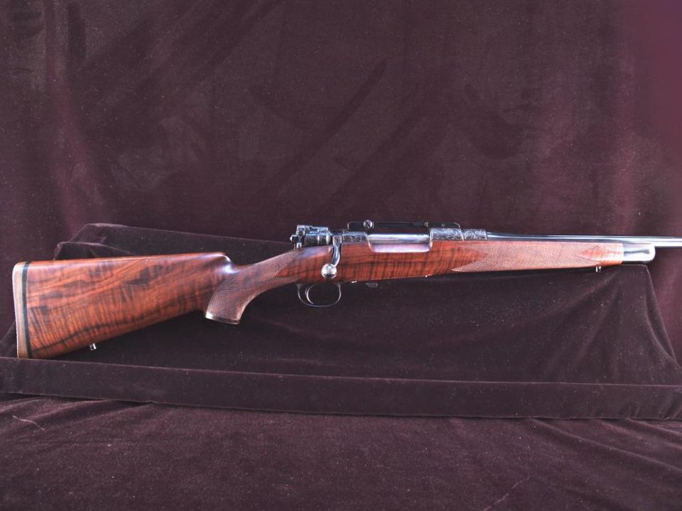 Vintage rifle with wooden stock and engraved metal receiver.