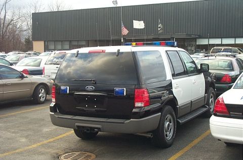 2001 Ford Crown Victoria - A black and white police SUV is parked in a lot with other vehicles.