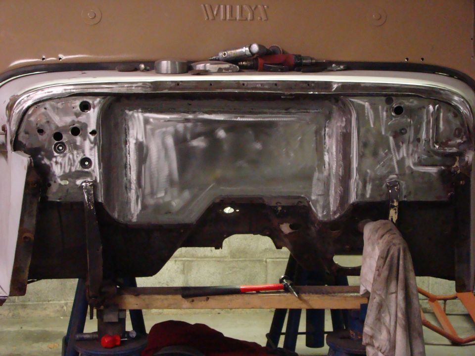 Close-up of a vehicle's firewall and inner fender wells, showing metal prep and tools.