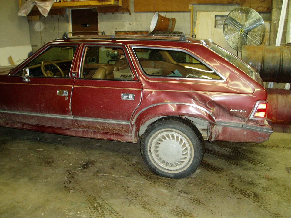 Damaged dark red station wagon, rear passenger side dented.