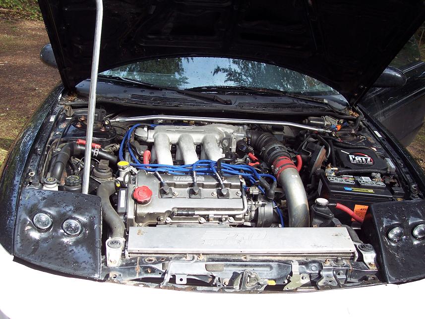 1995 Ford Probe engine bay with hood open, showing engine, blue wires, and silver intake.