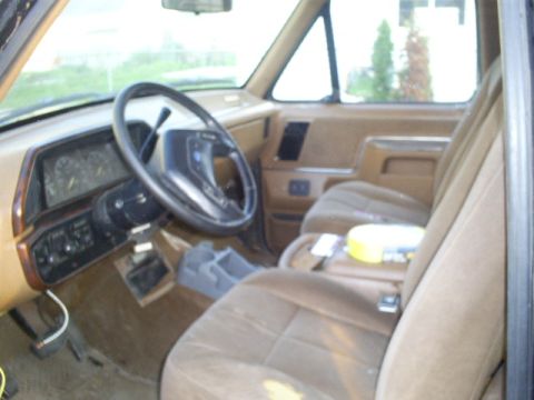 Interior of a 1990 Ford Bronco, showing dashboard, steering wheel, and tan seats.