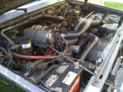 1990 Ford Bronco engine bay with V8 engine, hoses, wiring, and battery.