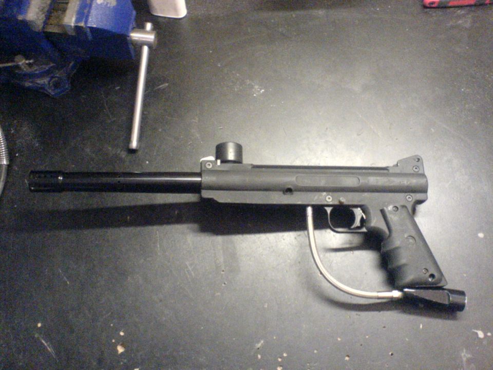 Black paintball gun with a silver hose attached to the bottom.