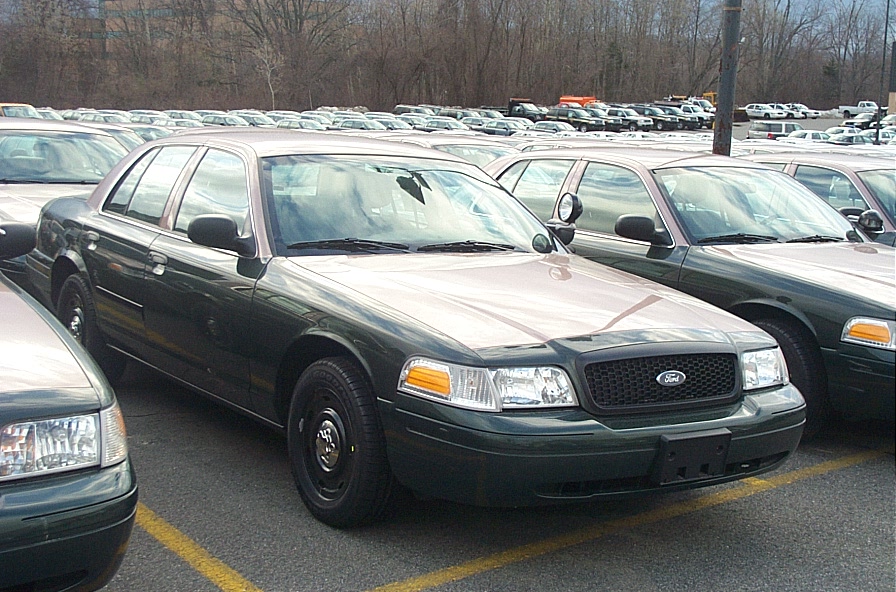 Dark green Ford Crown Victoria police sedan parked in a lot full of sedans