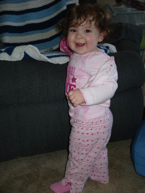 2000 Ford Crown Victoria - A young child with curly brown hair is smiling and looking at the camera while standing next to a dark green couch with a striped blanket.…