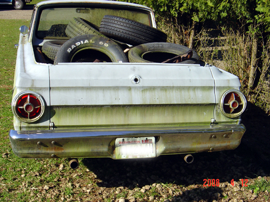 Rear view of a light-colored pickup truck with tires in the bed.