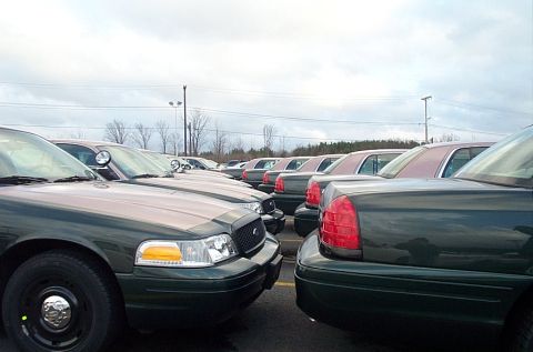 2001 Ford Crown Victoria - A line of Ford Crown Victoria police cars are parked side-by-side in an outdoor lot.