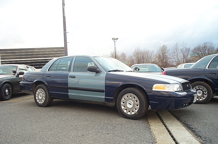 Two-tone Ford Crown Victoria with blue front and light blue rear doors, parked next to other similar cars