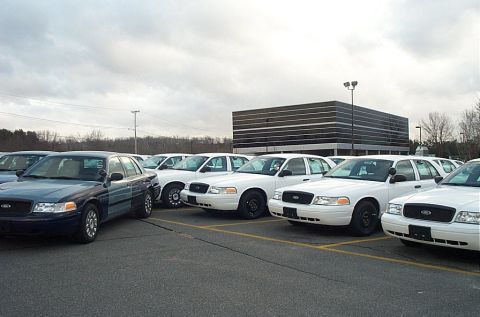 2001 Ford Crown Victoria - A dark blue 2001 Ford Crown Victoria is parked in a lot with several white models, suggesting a fleet or dealership setting.