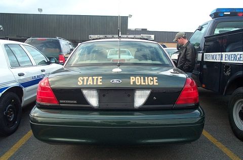 2001 Ford Crown Victoria - A dark green Ford Crown Victoria police car is parked next to other emergency vehicles.