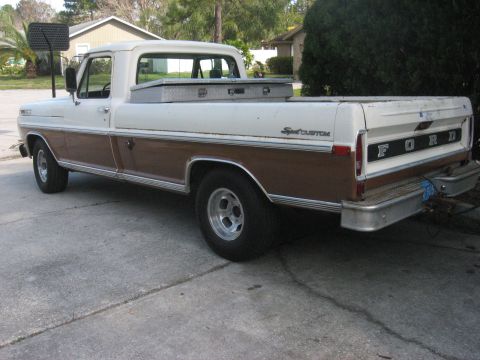 1972 Ford F-100 - The rear driver's side of a two-tone brown and white 1972 Ford F-100 pickup truck is shown parked on a concrete driveway. A silver toolbox…