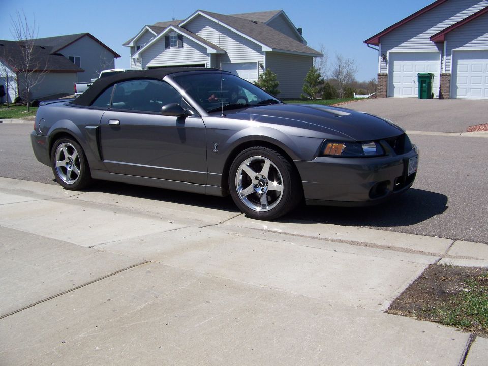 Dark gray convertible Mustang parked on a driveway.