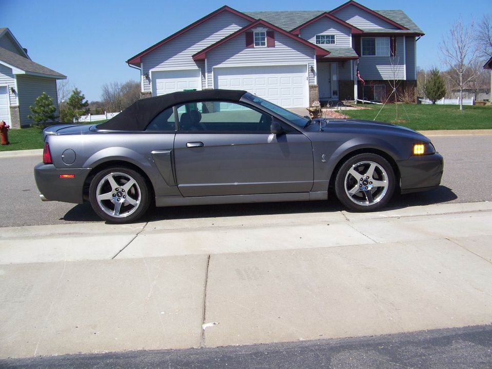 Dark gray convertible Mustang parked on a residential street.