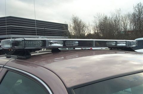 2001 Ford Crown Victoria - A light bar is mounted on the roof of a brown 2001 Ford Crown Victoria.