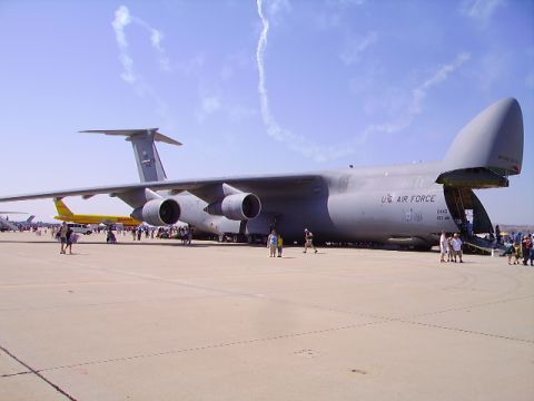1990 Ford Bronco - A large gray U.S. Air Force cargo plane is parked on an airfield with its rear cargo door open. Several people are visible near the plane a…