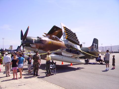 1990 Ford Bronco - A camouflaged Douglas A-1 Skyraider aircraft is on display with its bomb racks open, featuring the text "NAKED FANNY" on its nose. Several…