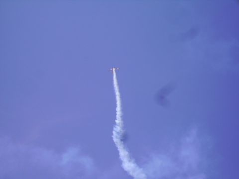1990 Ford Bronco - An airplane is performing an aerial maneuver, leaving a smoke trail against a clear blue sky.
