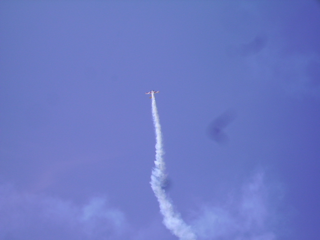 Airplane performing an aerial maneuver with a smoke trail.