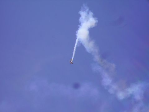 1990 Ford Bronco - A small airplane performs an aerial maneuver, leaving a white smoke trail against a clear blue sky.